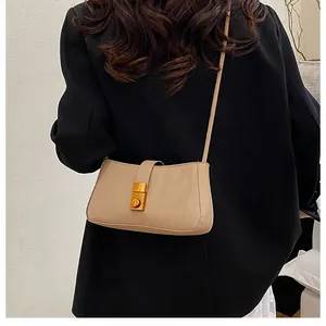 Beige matte leather underarm bag shown as a crossbody on a black suit jacket