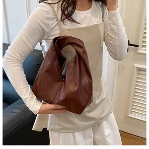 Detail einer dunkelbraunen Falten-Eimertasche mit geknotetem Griff für stilvolle Damen