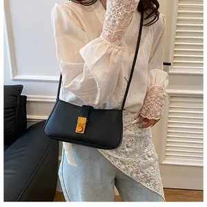 Detail of a minimalist black leather shoulder bag with a rectangular gold metal buckle