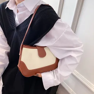 Sac bandoulière vintage en toile et cuir marron porté par un mannequin en intérieur