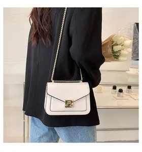 Close-up of white crossbody bag with gold chain strap worn on a black blazer