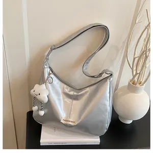 Zilveren metallic hobo tas met een witte pluchen wolk hanger en mode-etiket