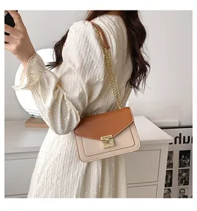 Detail of a brown and beige chain strap crossbody bag with golden square metal twist lock