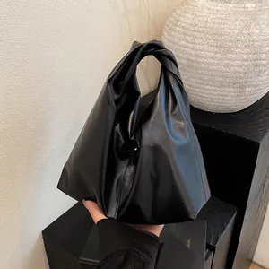 Minimalistische schwarze Beuteltasche mit Knotengriff und glänzender Lederoptik