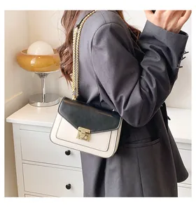 Detail of minimalist black and white crossbody bag with gold chain and metal lock
