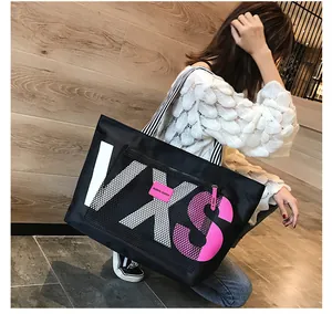 Detail of spacious black tote bag with VXS logo and striped strap shown on a model