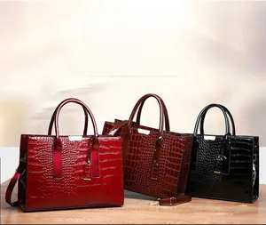 Three crocodile embossed tote bags in red, brown, and black with shiny finish