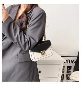 On-shoulder view of a chic black and cream crossbody bag with gold chain and metal lock