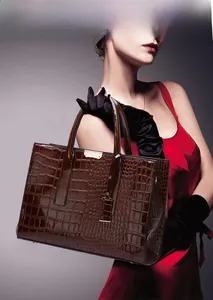 Close-up of deep brown crocodile embossed patent leather handbag with gold hardware