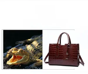 Detail of wine red crocodile embossed texture leather and metallic hardware on handbag