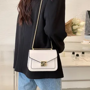 Chic white crossbody chain bag with gold lock buckle shown on model in urban style