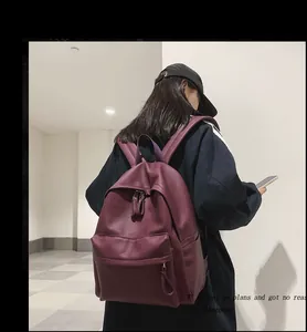 Detailed back view of a burgundy leather backpack with荔枝 pattern on a model