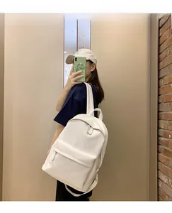 Side view of a minimalist white PU leather backpack for women shown in a lifestyle setting