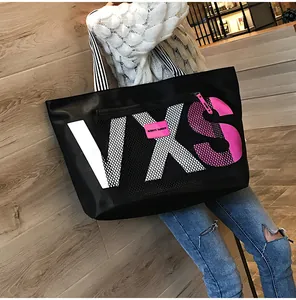 Detail of black tote bag with VXS lettering print and front mesh zipper pocket