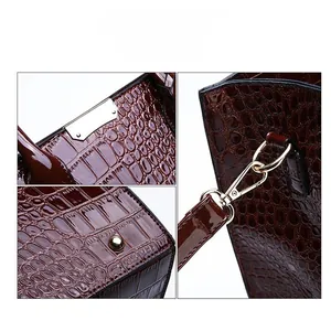 Macro detail of glossy crocodile embossed faux leather and light gold hardware on handbag