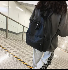 Detail of a minimalist black PU leather backpack with lychee texture on model in street view