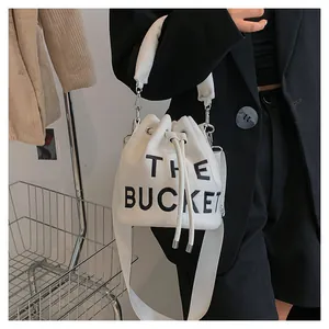 Detail of cream plush bucket bag with bold black The Bucket text and drawstring