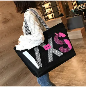 Detail of a black large tote bag with pink VXS letter print and striped shoulder strap