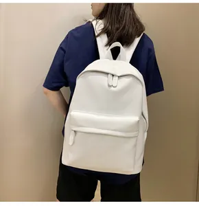 Detail of minimalist white PU leather backpack showing fine texture and sleek front pocket