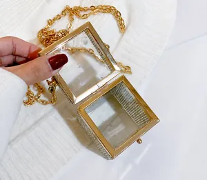 Macro detail of sparkly rhinestone mini box bag with gold metal frame and chain strap