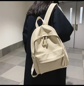 Detail view of cream PU leather backpack featuring lychee texture and side pocket