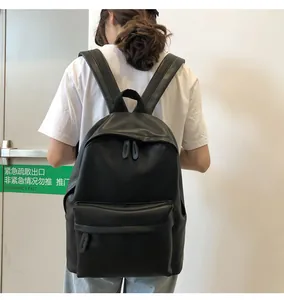 Rear view of a model wearing the minimalist black PU leather school backpack