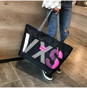 Detail of black tote bag with VXS letters, striped handle and mesh zipper pocket