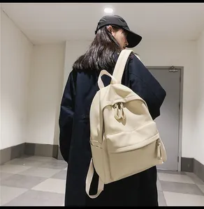 Side view of cream-colored pebble leather backpack shown on person in a minimalist hallway