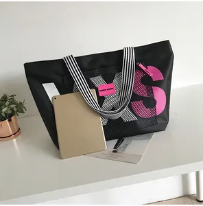 Black nylon tote bag with large XS lettering showing spacious interior for a tablet