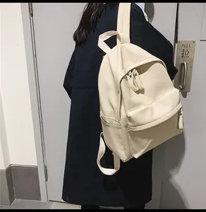 Side view of model wearing a cream-colored faux leather backpack with litchi texture