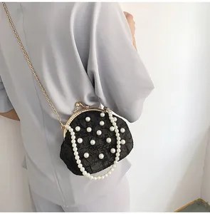 Λεπτομέρεια μαύρης πλισέ τσάντας clutch με λευκές πέρλες και χρυσή μεταλλική αλυσίδα