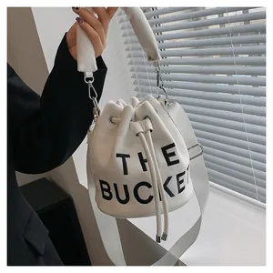 Detail of the white canvas bucket bag with large black lettering and drawstring closure