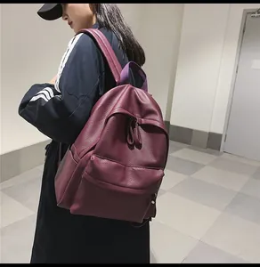 Burgundy faux leather backpack with litchi texture and front pocket shown on model