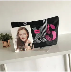 Detail of large black tote bag featuring pink XS print and striped woven handles