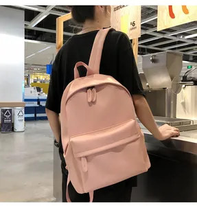 Detail shot of light pink PU leather backpack with minimalist dual zippers and front pocket
