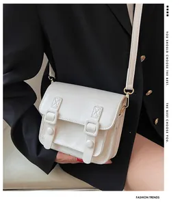 Detailopname van witte leren crossbody tas met gespen gedragen op een zwart jasje