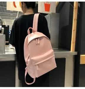Rear view of a pink matte PU leather backpack shown on model in a minimalist setting