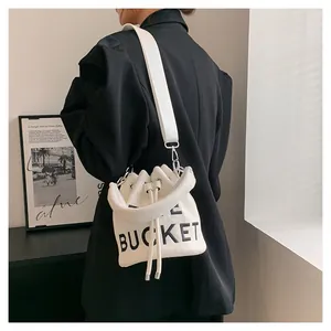 Detail of off-white canvas bucket bag with black BUCKET print and wide shoulder strap