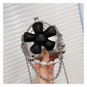Detail of silver kiss-lock mini bag with large black leather flower and pearl handle