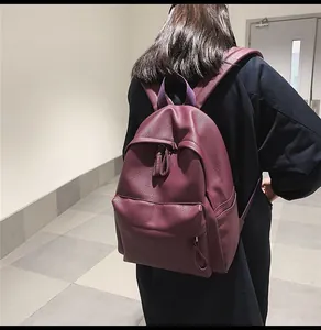 Rear view of a model wearing the purple textured faux leather backpack in a minimalist hallway