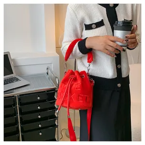 Detail of red velvet bucket bag with drawstring and THE BUCKET embossing on a soft strap