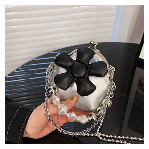 Detailed shot of mini silver crossbody bag with a large black 3D flower and pearl chain