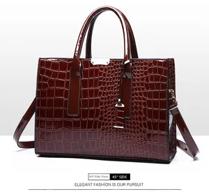 Detail view of burgundy crocodile pattern handbag with glossy finish at 45 degree angle