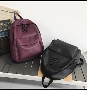 Close-up of stylish purple and black PU leather backpacks on a vintage metal table