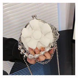 Detail of mini white faux leather bag with 3D floral accent and pearl chain strap