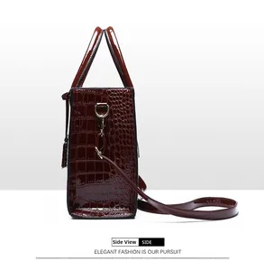 Detail view of burgundy crocodile pattern handbag showing side profile and gold hardware