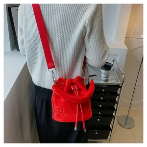 Detail of red velvet bucket bag featuring embossed BUCKET text and nylon strap