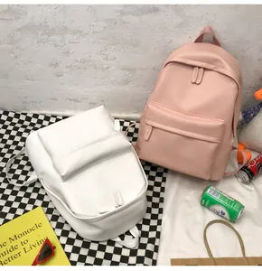 Close-up of pink and white minimalist PU leather backpacks with front zipper pockets