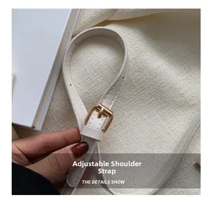 Detail van verstelbare crème kunstlederen schouderriem met gouden gesp en fijne stiksels