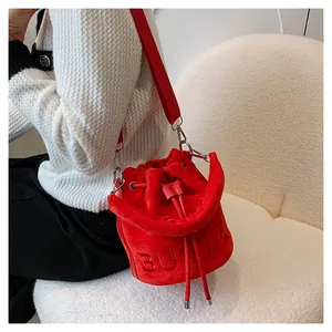 Detail of red velvet bucket bag with BUCKET relief and drawstring closure on shoulder